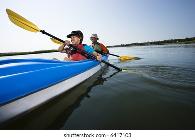 Low Angle Of African American Middle-aged Man And Woman Paddling Kayak.