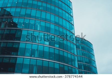 Low Angle Architectural Exterior of Modern Commerical Office Building with Round Glass Facade in Financial District on Overcast Day with Cloudy Gray Sky and Copy Space, London, England