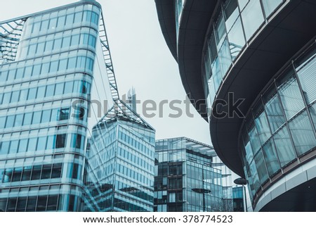 Low Angle Architectural Exterior View of Modern Commerical Office Buildings with Glass Facades in Financial District on Overcast Day with Gloomy Gray Sky in Urban London Setting, England, UK