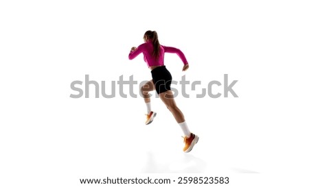 Low angle back view image of young sportive woman, running athlete in motion, training isolated on white studio background. Concept of athletics, sport, endurance, fitness, healthy lifestyle. Ad