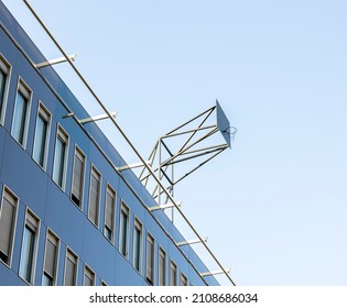 A low angle of a basketball hoop on top of a building under a clear blue sky