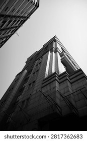 Low angle black and white view of a tall modern building with strong geometric lines against a bright open sky