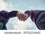 Low angle, blue sky and couple with love, holding hands and romance with adventure, relationship and bonding together. Closeup, touching palms and people with trust, marriage and nature with kindness