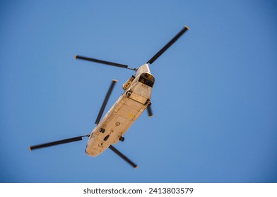 a low angle bottom view of a helicopter flying in the blue sky