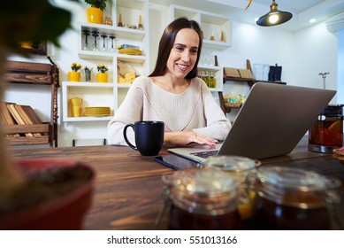 Low angle of Caucasian woman working at home in front of a laptop. Using touchpad. Young businesswoman working at home in the morning 