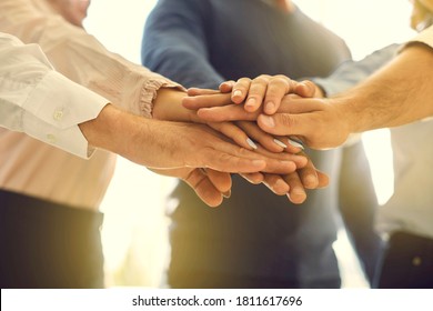 Low angle close up of people stacking hands making agreement and starting new business. Startup team members setting goals. Group of loyal company workers joining hands in team building meeting