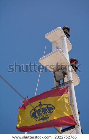 Low angle close up of Spanish flag and mast lights during bright summer cruise in Canary Islands.