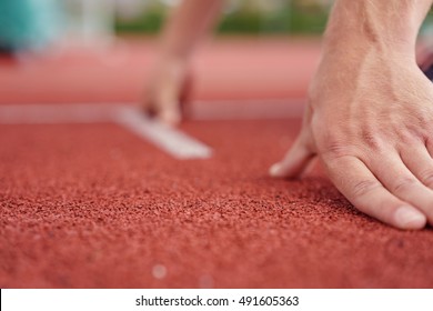 Low Angle Close Up View Of The Hands Of An Athlete On A Race Track Bending Down In The Starter Position In A Conceptual Image Of Competition And Challenges