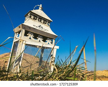 A Low Angle Closeup Shot Of A Beautiful Lantern On The Ground On The Tall Grass Under The Blue Sky