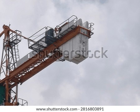 Low angle close-up of a tower crane counterweight with concrete blocks against a cloudy sky background.