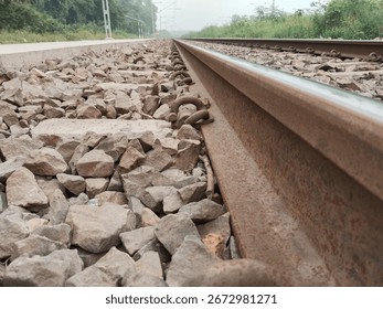 Low angle closeup view from beneath the railway track showing stones, sleepers, and rail infrastructure from ground level perspective, captured for industrial and transportation context