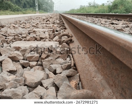 Low angle closeup view from beneath the railway track showing stones, sleepers, and rail infrastructure from ground level perspective, captured for industrial and transportation context