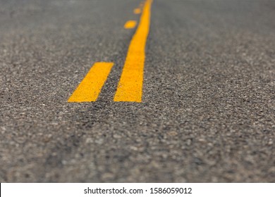 Low angle closeup view of yellow dividing and no passing lines and stripes in middle of asphalt road - Shutterstock ID 1586059012