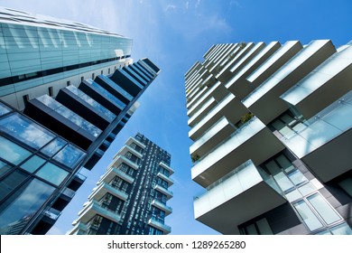 Low angle converging perspective of modern Milan skyscrapers with large balconies against a clear sunny blue sky