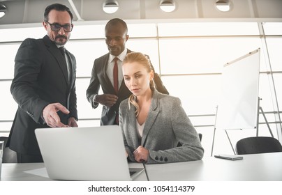 Low Angle Of Coworkers Focused On Laptop On The Table. Copy Space In Right Side