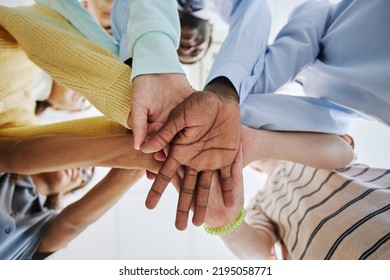 Low angle of diverse schoolchildren stacking hands and huddling in team exercise in classroom - Shutterstock ID 2195058771