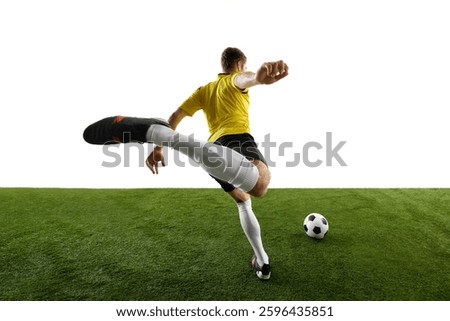 Low angle dynamic back view image of man, soccer player playing with intensity and focus, kicking ball on green stadium against white background. Concept of sport, action, competition, game. Ads