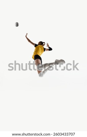 Low angle dynamic image of competitive and focused young woman, volleyball player in motion during game, jumping and hitting ball isolated on white background. Concept of sport, effort, agility
