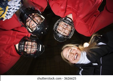 Low angle of female hockey players in huddle with coach smiling. - Powered by Shutterstock