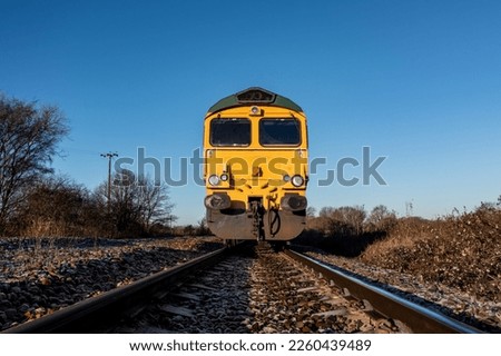 A low angle front point of view of a freight locomotive engine approaching a trespasser on a railway line in an industrial safety image with copy space