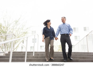 Low angle full length front view of mature couple holding hands descending stairs - Powered by Shutterstock