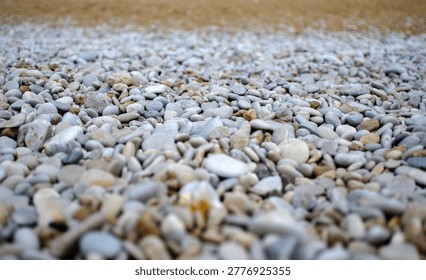 Low angle ground perspective looking straight across a vast endless expanse of countless small perfectly smooth grey beach pebbles stretching to the horizon.