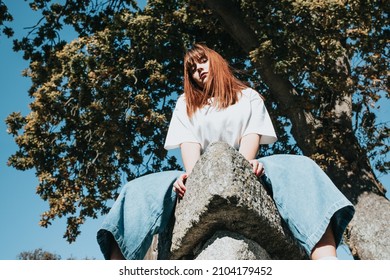 Low Angle Image Of A Body Positive Modern Girl On Jeans And White Shirt With Copy Spac, Trees And Sky Background. Modern Fashion Campaign Ad Concept. Bright Girls World Feminism And Strong Woman