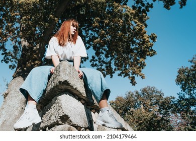 Low Angle Image Of A Body Positive Modern Girl On Jeans And White Shirt With Copy Spac, Trees And Sky Background. Modern Fashion Campaign Ad Concept. Bright Girls World Feminism And Strong Woman