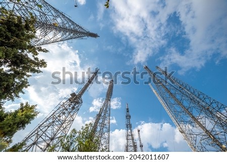 Low angle image of metallic communication towers with blue sky and some clouds