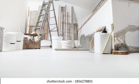 Low Angle Of Indoor Shot Of Construction Or Building Site Of Home Renovation With Tools On White Floor With Paint Buckets And Primer Jerry Can