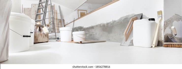 Low Angle Of Indoor Shot Of Construction Or Building Site Of Home Renovation With Tools On White Floor With Paint Buckets And Primer Jerry Can