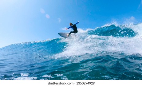 LOW ANGLE, LENS FLARE: Cheerful Surfer Riding Big Foaming Ocean Wave In Sunny Nature. Stoked Man Having Fun Surfing A Large Wave On His Cool Surfboard In The Summer Sun Near The Idyllic Canary Islands