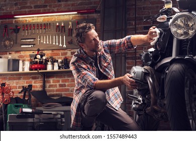 Low angle of a man polishing classic vintage motorcycle in garage or workshop  - Powered by Shutterstock