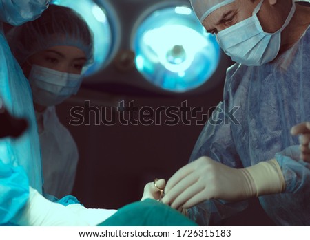 Low angle of medical professionals in sterile masks and uniform doing operation together stock photo