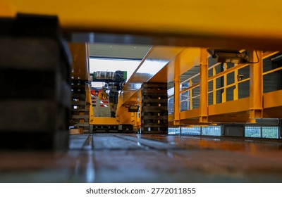 Low angle perspective below industrial overhead crane structure with steel beams and warehouse interior used for heavy manufacturing operations.