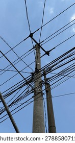 Low angle perspective of chaotic electrical cables against blue sky