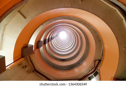 Low angle perspective from the circular atrium of a multistorey public housing estate in Hong Kong with sunlight cast from top of the tower & multilayers of corridors making a unique eccentric pattern