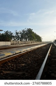Low angle perspective of empty railway tracks stretching into the horizon under a clear blue sky