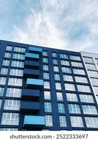 Low angle perspective High-rise rectangular Residential building against the blue sky. Modern architecture. Detail New high rise House facade with windows. Real Estate business concept.