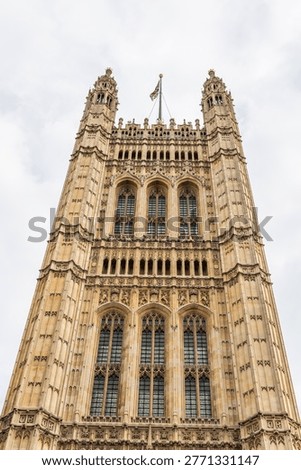 A low angle perspective looking up at the historic Victoria Tower of the Palace of Westminster in London, showcasing intricate gothic revival architecture.