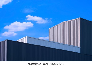 Low angle and perspective side view of corrugated metal factory buildings in modern style against blue sky background 