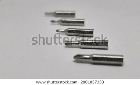 Low angle perspective of some interchangeable metal screwdriver bits with sharp selective focus on the center and blurry back and front.