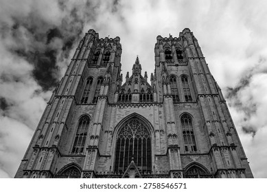 Low angle perspective view on Facade of the Cathedral of Brussels or Cathedral of St. Michael and St. Gudula in Brussels, Belgium under dramatic cloudy sky. Black and white contrast scene