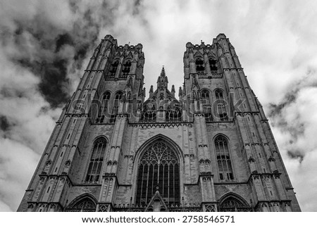 Low angle perspective view on Facade of the Cathedral of Brussels or Cathedral of St. Michael and St. Gudula in Brussels, Belgium under dramatic cloudy sky. Black and white contrast scene