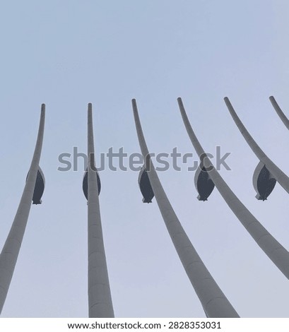 Low angle perspective view of tall white curved monument columns reaching up into clear sky