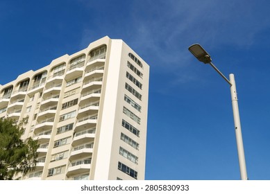 Low angle perspective of a white modern apartment building with balconies against a vibrant deep blue sky.