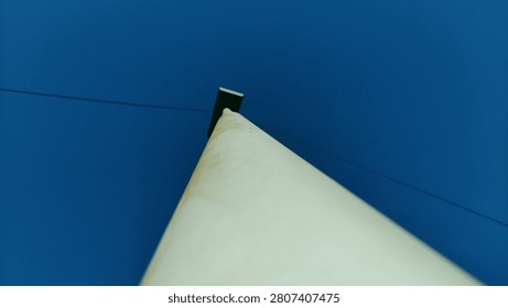 A low angle perspective of a white pole reaching towards a clear blue sky.