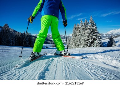 Low angle photo of the alpine skier with focus on the ski between legs stand on the track over beautiful snowy forest after snowfall