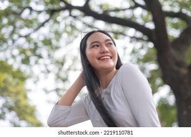 A Low Angle Photograph Of A Beautiful Asian Woman Posing Outside The Park.