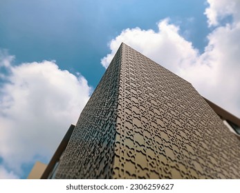 Low angle photography of islamic pattern wall details of high-rise buildings. Architectural Exterior Against Blue Sky with White Clouds.